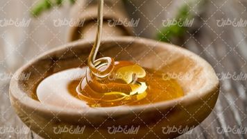 تصویر با کیفیت ظرف عسل همراه با عسل و ظرف چوبی