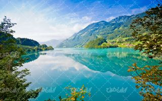 تصویر با کیفیت منظره زیبای دریاچه همراه با آسمان آبی و درختان