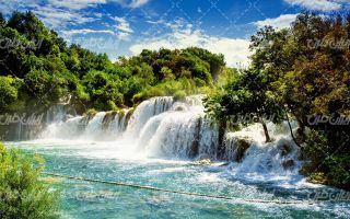 تصویر با کیفیت منظره آبشار همراه با صخره و آسمان آبی