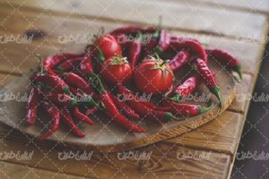 تصویر با کیفیت فلفل قرمز همراه با تخته آشپزی و گوجه فرنگی