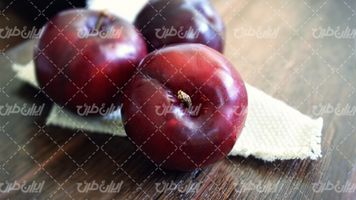 تصویر با کیفیت سیب قرمز همراه با میوه و سطح چوبی