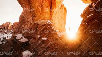 تصویر با کیفیت غروب آفتاب همراه با صخره و برف روی صخره