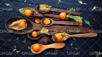 تصویر با کیفیت قاشق چوبی همراه با گوجه فرنگی و سطح چوبی