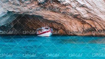 تصویر با کیفیت صخره همراه با قایق تفریحی و دریا
