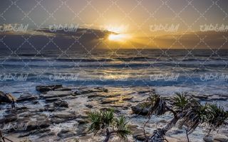 تصویر با کیفیت دریایی مواج همراه با ساحل دریا و منظره غروب خورشید