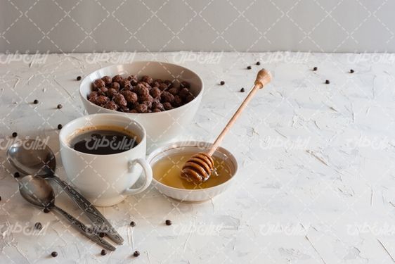 تصویر با کیفیت فنجان قهوه همراه با ظرف عسل و قاشق