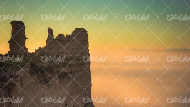 تصویر با کیفیت منظره زیبا همراه با چشم انداز غروب خورشید و صخره