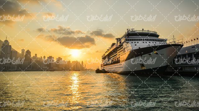 تصویر با کیفیت منظره زیبای غروب آفتاب همراه با کشتی و شهر ساحلی