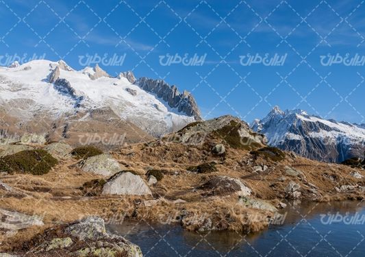 تصویر با کیفیت منظره زیبای کوه برفی همراه با دریاچه و آسمان آبی