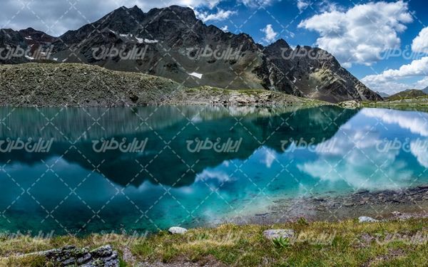 تصویر با کیفیت دریاچه به همراه آسمان آبی و کوه سنگی