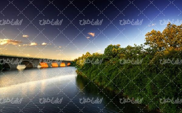 تصویر با کیفیت منظره زیبای غروب آفتاب همراه با پل و رودخانه