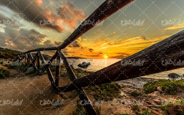 تصویر با کیفیت منظره زیبای غروب آفتاب همراه با دریاچه و حصار چوبی