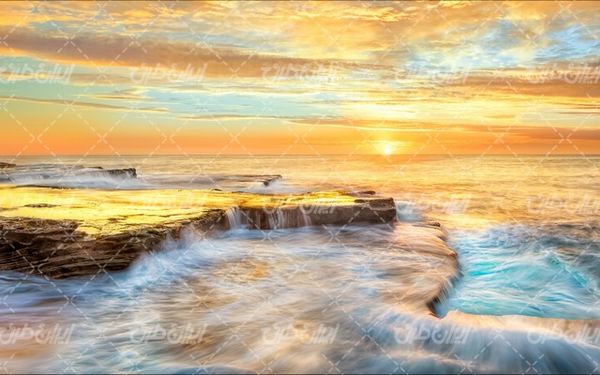 تصویر با کیفیت منظره زیبای غروب آفتاب همراه با دریا و صخره