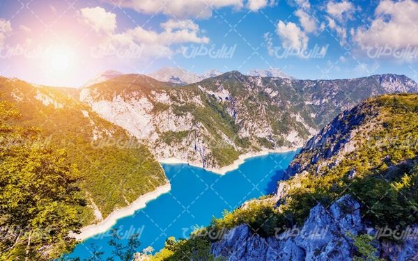 تصویر با کیفیت منظره زیبای رودخانه همراه با درخت و آسمان آبی