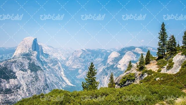 تصویر با کیفیت کوهستان به همراه آسمان آبی و درختان