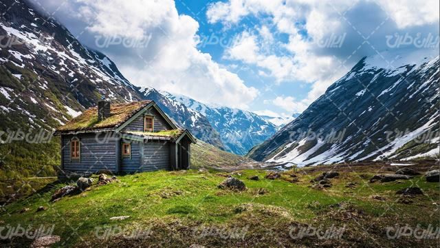 تصویر با کیفیت منظره زیبای کوهستان همراه کلبه چوبی و برف روی کوه