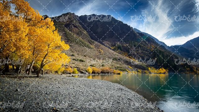 تصویر با کیفیت دریاچه همراه با فصل پاییز و منظره کوه