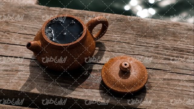 تصویر با کیفیت قوری چای همراه با دم نوش و سطح چوبی